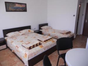 a bedroom with two beds and a table and chairs at "Aхтополис" - подсигурено безплатно паркиране in Ahtopol