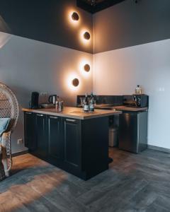 a kitchen with black cabinets and a counter top at La Ronde des Bois - Romance et Bien Être - Jacuzzi privatif-piscine-patio in Mellecey