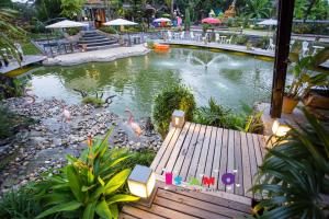 a pond in a garden with a wooden deck at Is Am O Chiang Mai Resort in San Sai