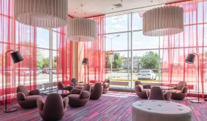 a lobby with chairs and tables and large windows at Park Inn by Radisson Volgograd in Volgograd