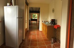 a kitchen with a white refrigerator and a tile floor at The Magnolias B&B in Moyon