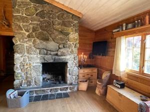 a living room with a stone fireplace in a cabin at Bjørnehiet Havsdalen in Geilo
