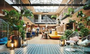 una hall con molte piante, tavoli e sedie di Hotel Gilbert a Vienna