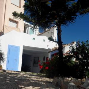 a white building with a blue door and a palm tree at Charming house ideal for couples and young families in Tárbena