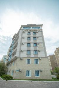 a tall white building with blue windows at SULO Apartments in Atyraū