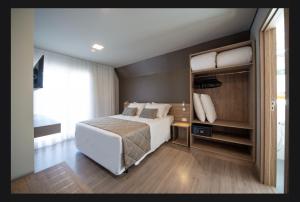 une chambre avec un lit blanc et une grande fenêtre dans l'établissement Laghetto Resort Golden Gramado, à Gramado 8 autres photos