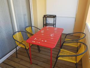 een rode tafel en stoelen op een balkon bij Studio à moins de 50m de l'école de voile... in La Turballe