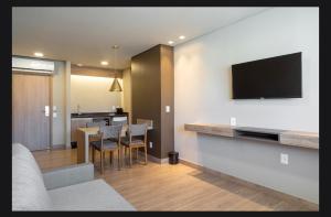 un salon avec une télévision et une table avec des chaises dans l'établissement Laghetto Resort Golden Gramado, à Gramado