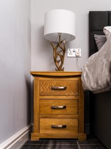 a lamp on a dresser next to a bed at The Juniperlea Inn in Pathhead