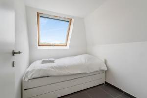 a small bedroom with a bed with a window at Walhofpark 24 in De Panne