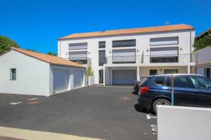 Un coche aparcado en un estacionamiento frente a un edificio. en Appartement neuf, 150m de la grande plage, parking, proche commerces, en Saint Gilles Croix de vie