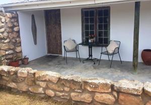 a patio with a stone wall and two chairs and a table at Wild Rescue Nature Reserve in Riversdale