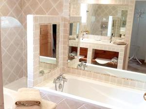 ein Badezimmer mit Badewanne, Waschbecken und Spiegel in der Unterkunft Villa raffinée à Orange avec piscine privée in Orange + 29 Fotos