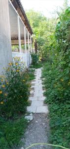 a stone walkway next to a house with flowers at Green House in Kachretʼi