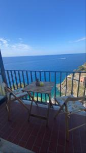 een tafel en stoelen op een balkon met uitzicht op de oceaan bij Sollevante Guest House in Riomaggiore