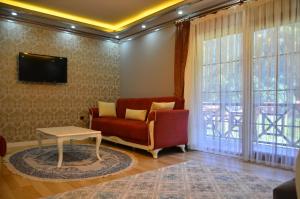 Kuzey Suite Otel في أوزونغول: غرفة معيشة مع أريكة حمراء وطاولة