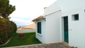 a white house with a green door and a yard at Casa Mansa in Porto Santo