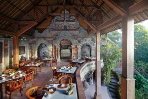 a restaurant with tables and chairs in a building at Hotel Tjampuhan Spa in Ubud
