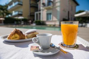 une tasse de jus d'orange à côté d'une assiette alimentaire dans l'établissement Villa Fiorita, à Cattolica