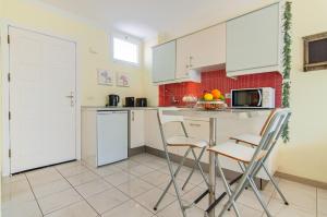 una cucina con mobili bianchi, tavolo e sedie di El Dorado Garden View PH04 ad Arona