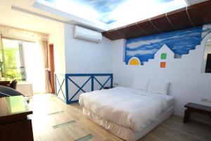 1 dormitorio con 1 cama con una pintura en la pared en 墾丁貝殼灣旅店, en Kenting