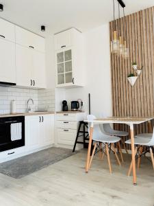 kuchnia z białymi szafkami, stołem i krzesłami w obiekcie Apartament Premium w mieście Słupsk