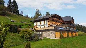 a large house on top of a green hill at Berggasthaus Agritur Moserhof in Braies