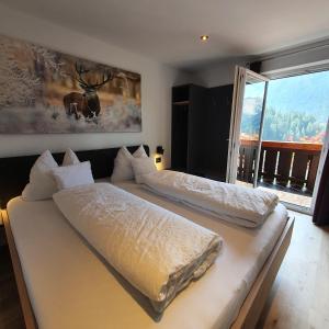 two beds in a room with a large window at Haus Herta B&B in Nova Levante