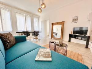 a living room with a blue couch and a table at Le Mans - Au Calme - Stationnement Facile - Proche Centre Ville et Gare in Le Mans