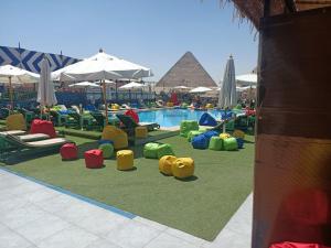 un resort con piscina con sedie colorate e piramide di Regency Pyramids Hotel a Il Cairo