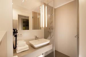 a white bathroom with a sink and a shower at th Hotel Leipzig Messe in Leipzig