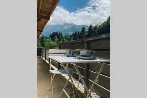 a table on a balcony with mountains in the background at La pépite des Aiguilles in Les Houches