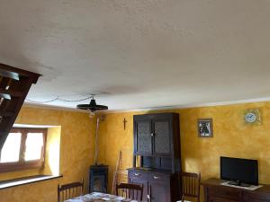 ein Esszimmer mit einem Tisch und einem TV sowie gelben Wänden in der Unterkunft Casa vacanze La Carbunera in Domodossola