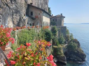 a building on the side of a cliff with flowers at Bnbook Casa dei Peschi - Lago di Monate in Cadrezzate