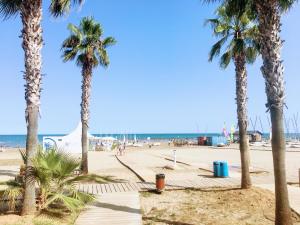 a beach with palm trees and the ocean at Piso vacacional con piscina en Benicassim in Benicàssim
