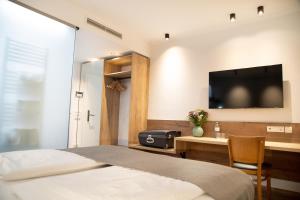 a bedroom with a bed and a desk with a television at Hotel Restaurant Auerhahn in Salzburg