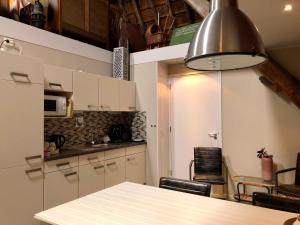 a kitchen with white cabinets and a table at Hoeve te Gast - vakantieboerderij in Groet