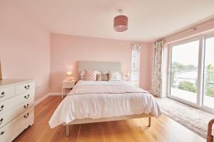 a white bedroom with a bed and a window at Lloret, Contemporary Retreat with Hot Tub, Waterside and Castle Views, Dog friendly in Laugharne