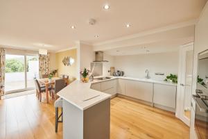 a kitchen with white cabinets and a dining room with a table at Lloret, Contemporary Retreat with Hot Tub, Waterside and Castle Views, Dog friendly in Laugharne
