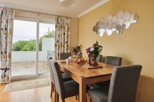 a dining room with a wooden table and chairs at Lloret, Contemporary Retreat with Hot Tub, Waterside and Castle Views, Dog friendly in Laugharne
