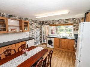 a kitchen with a dining table and a kitchen with a refrigerator at 8 Heatons Bridge Road in Ormskirk