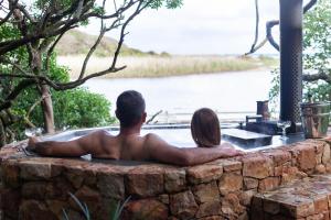 un hombre y una mujer sentados en una bañera en Kennedys Beach Villa, en Hermanus