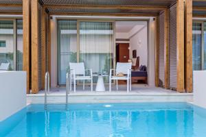 a pool with chairs and a table next to a house at Horizon Blu Boutique Hotel in Kalamata