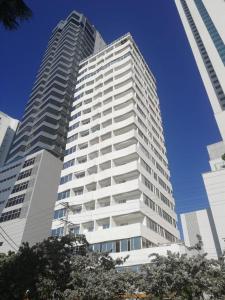 un edificio alto y blanco con árboles delante en Hotel Cartagena Premium, en Cartagena de Indias