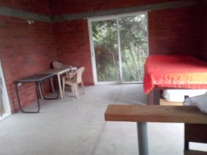 a room with a bed and a table and a window at Hospedaje Rural Misia Emilia in Medellín