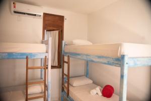 a room with two bunk beds and a doorway at Vila Mucugê Pousada e Hostel in Arraial d'Ajuda