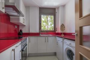 cocina roja con fregadero y lavadora en Apartamento ideal en Manresa, en Manresa