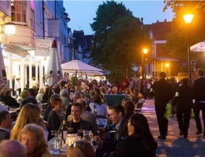 a crowd of people sitting at tables on a street at night at Studio Acorn private parking and garden in Royal Tunbridge Wells