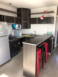 a kitchen with a black counter and red stools at Viví Home in Mar del Plata