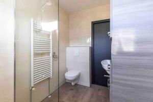 a bathroom with a toilet and a glass door at Casa The Wave with infrared sauna in Noordwijkerhout